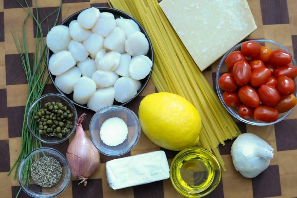 Ingredients for scallop pasta on a wooden cutting board