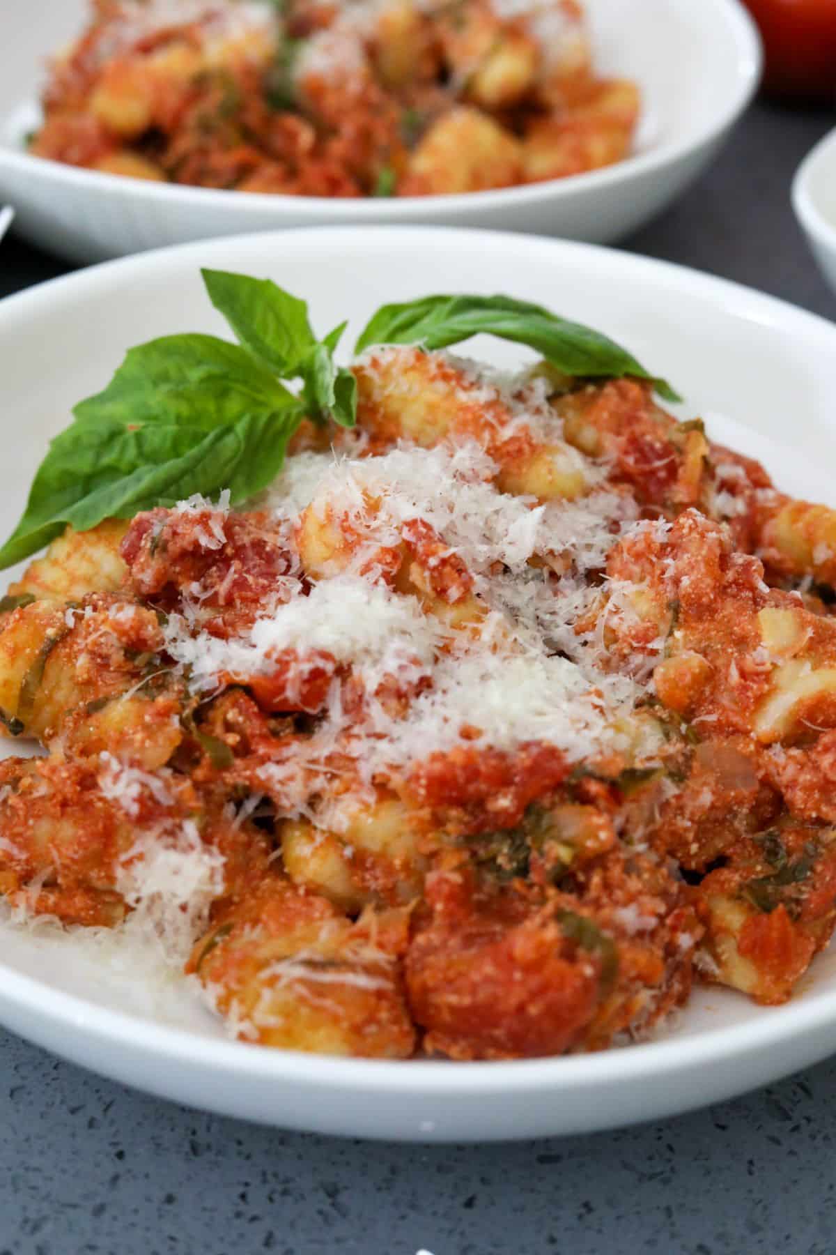 A white bowl with tomato and basil gnocchi