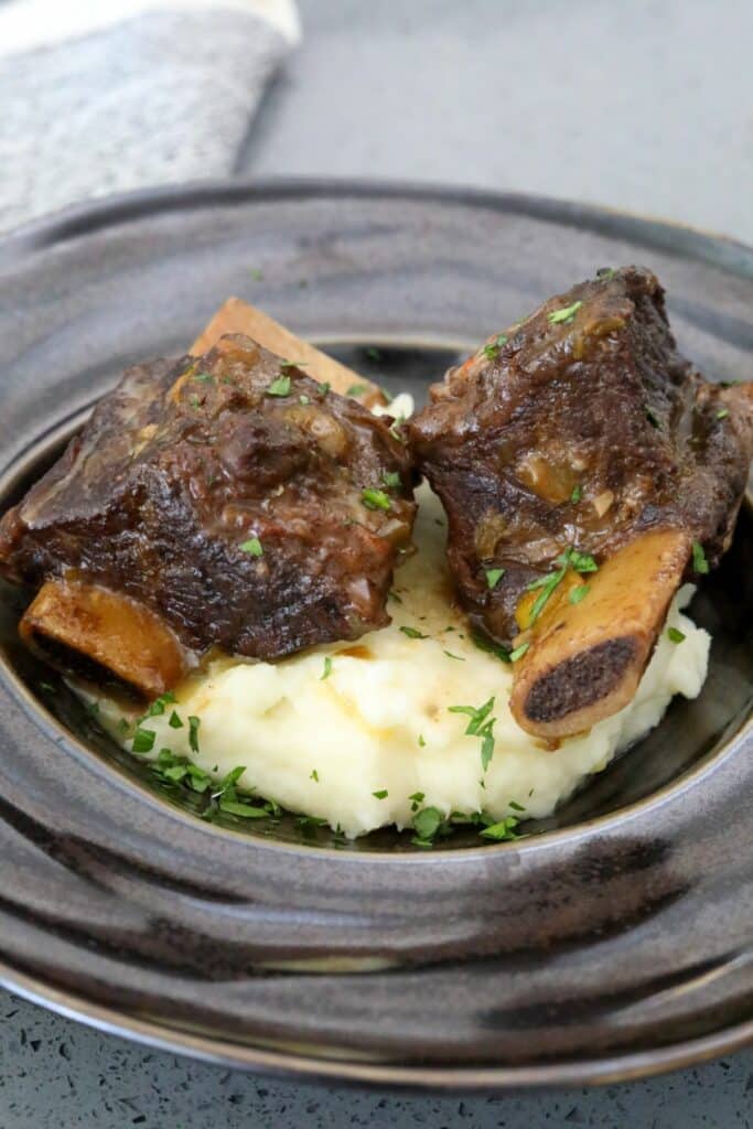 A serving of short ribs on mashed potatoes.