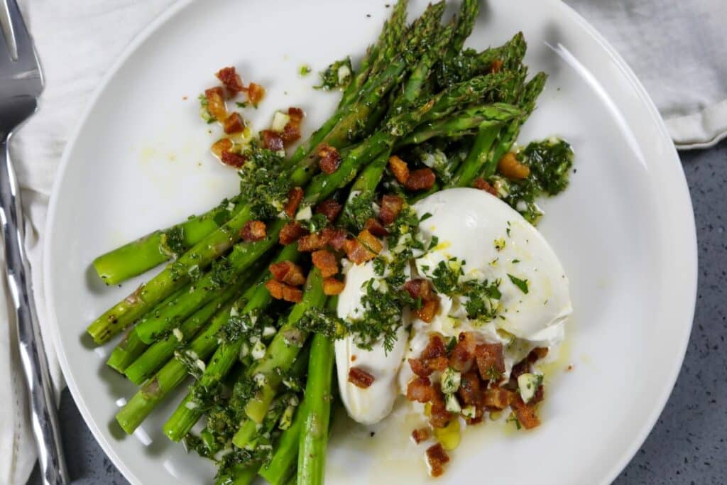 A white plate with asparagus with burrata