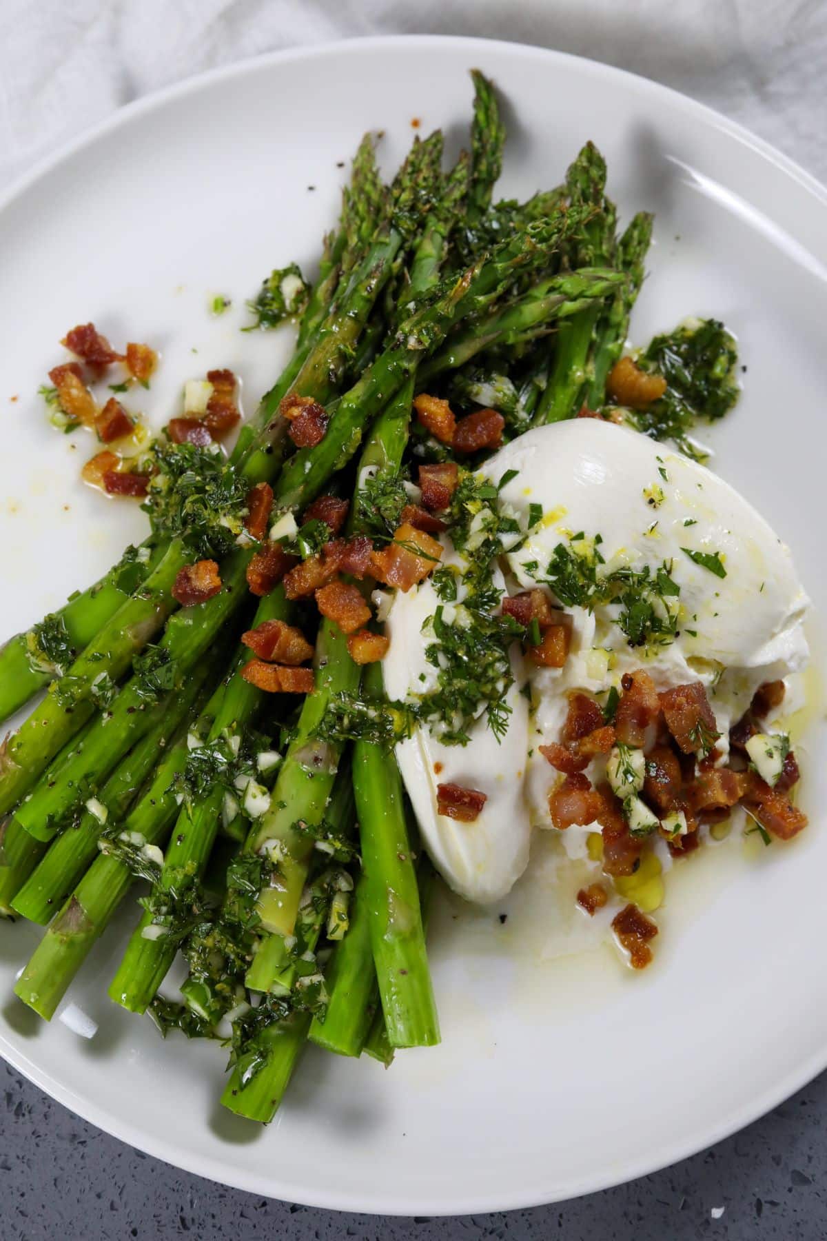 A plate with Asparagus with burrata and pancetta