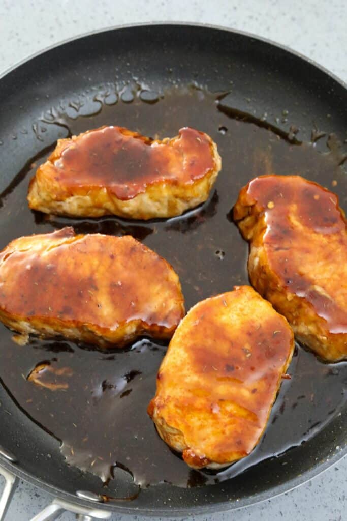Pork chops in a pan of balsamic glaze