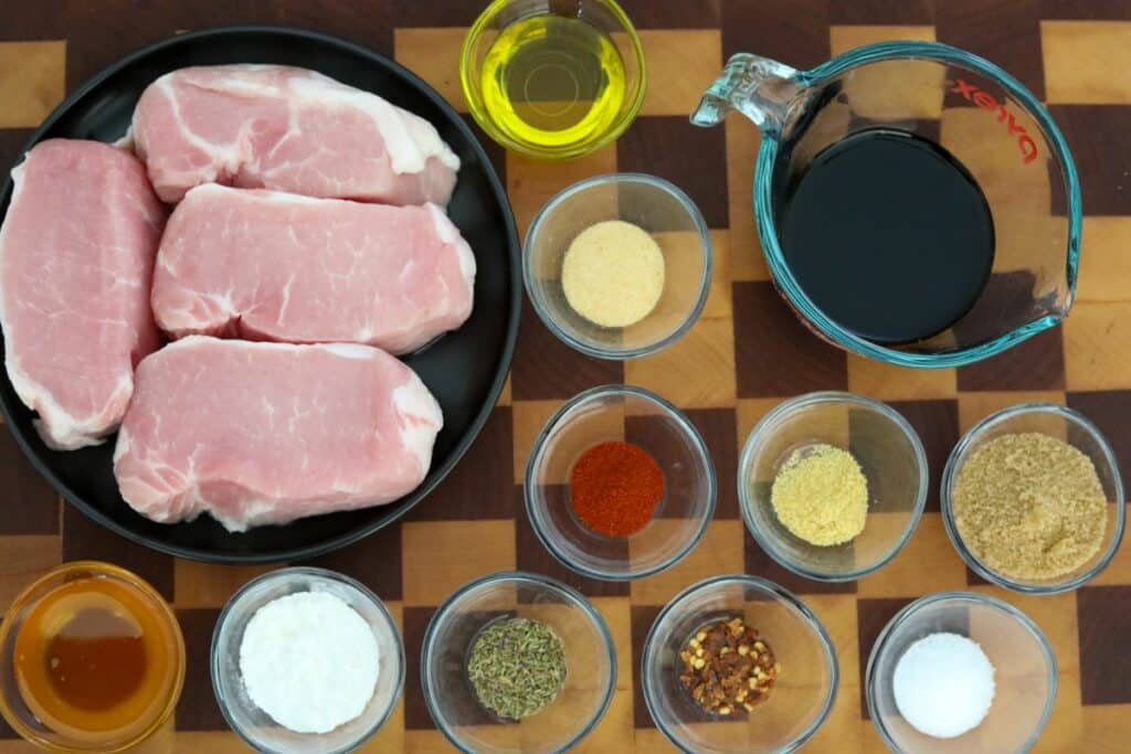Ingredients for glazed pork chops on a wooden cutting board
