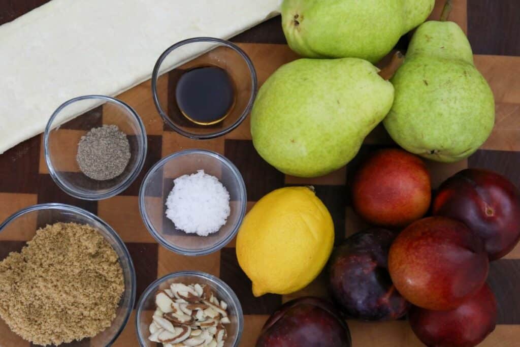 Ingredients for pear and plum tart on a wooden cutting board