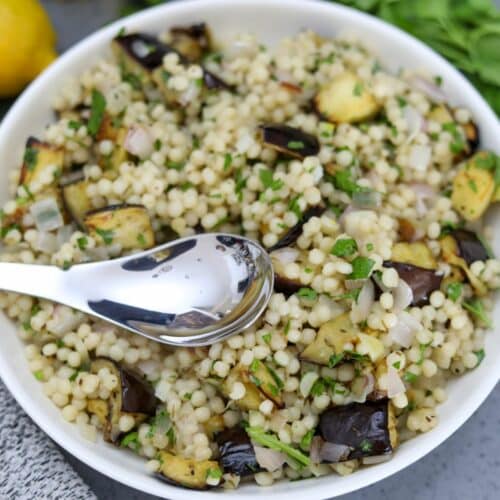 A spoon in a bowl of roasted eggplant Israeli couscous