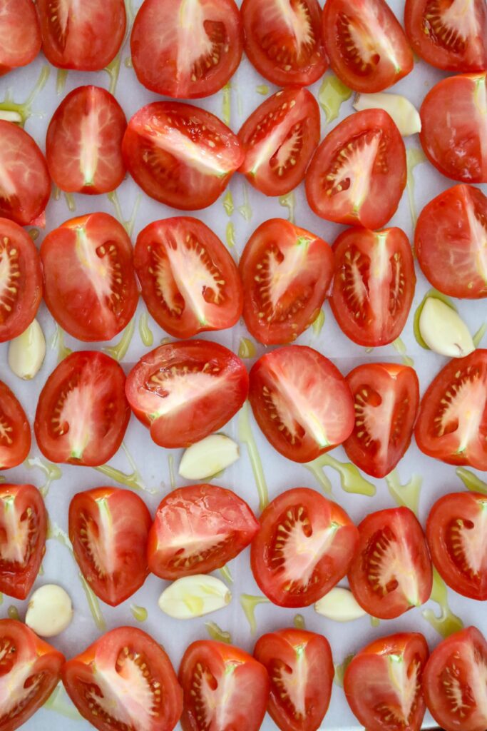 Quartered tomatoes and garlic on a lined sheet pan