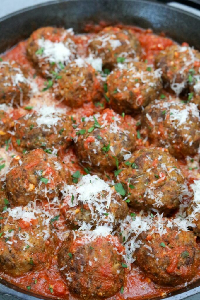 Meatballs covered in tomato sauce with parsley and cheese