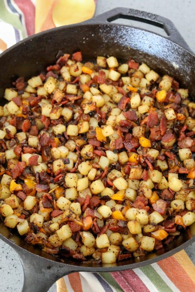 A cast iron skillet with cooked bacon potato hash