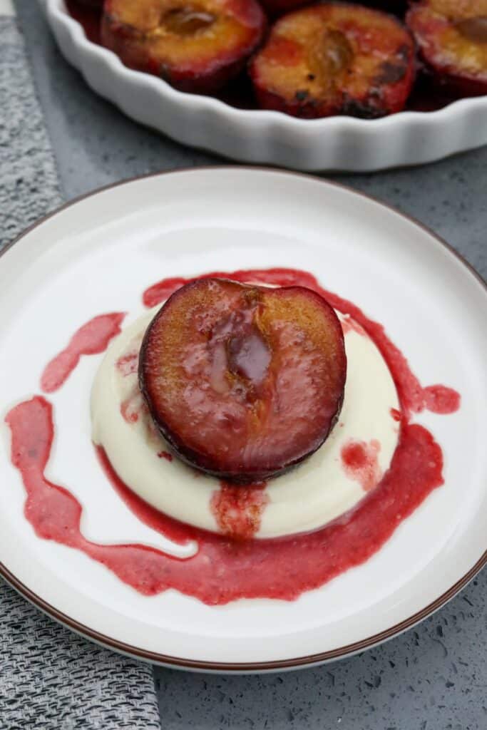 A while dish with a baked plum half on creme fraiche