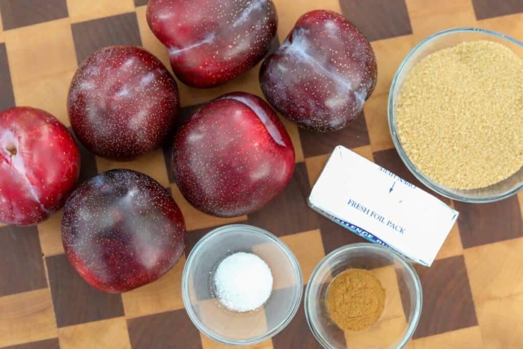 Ingredients for baked plums on a wooden cutting board