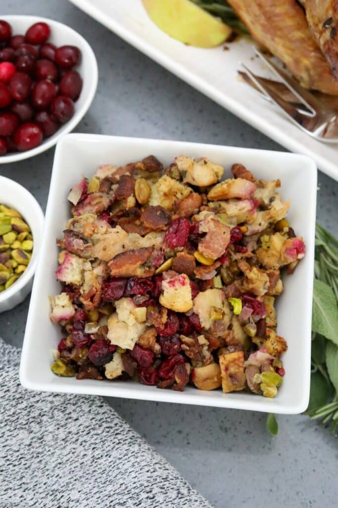 A white serving dish with cranberry and pistachio dressing