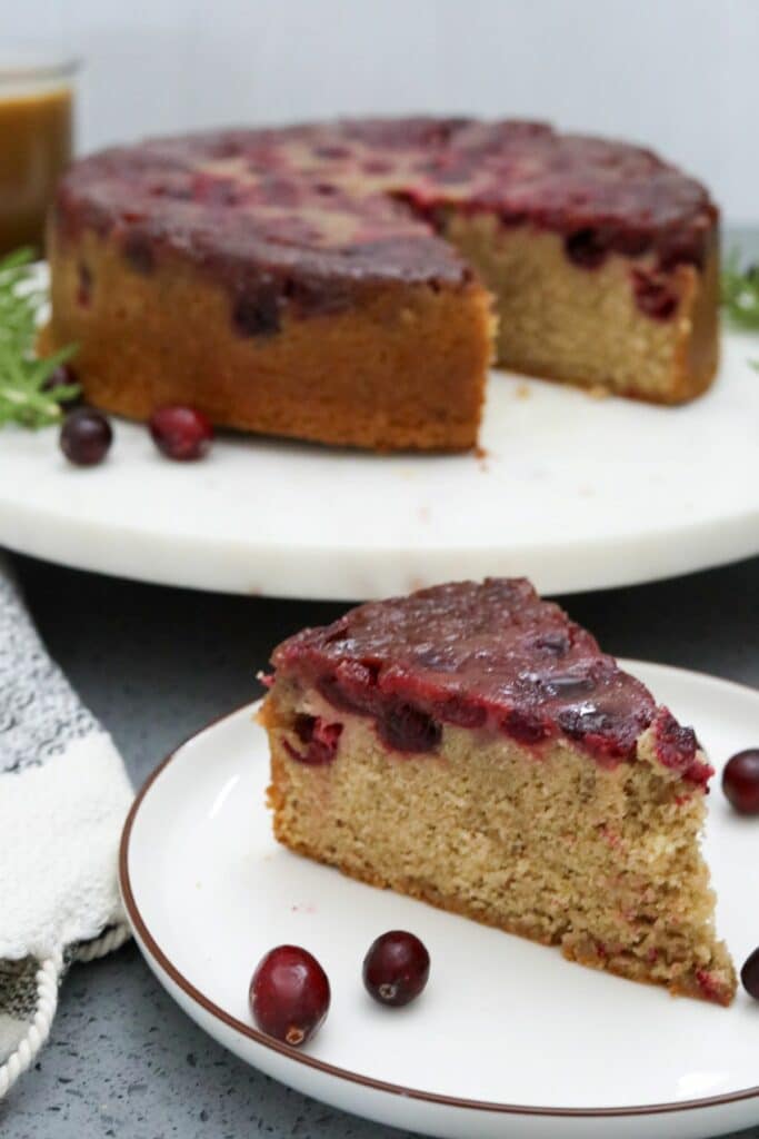 A slice of cranberry walnut upside down cake on a white plate