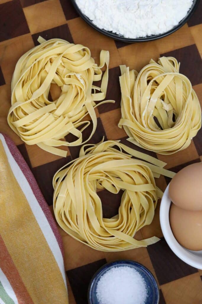 Three servings of fresh pasta on a wooden cutting board