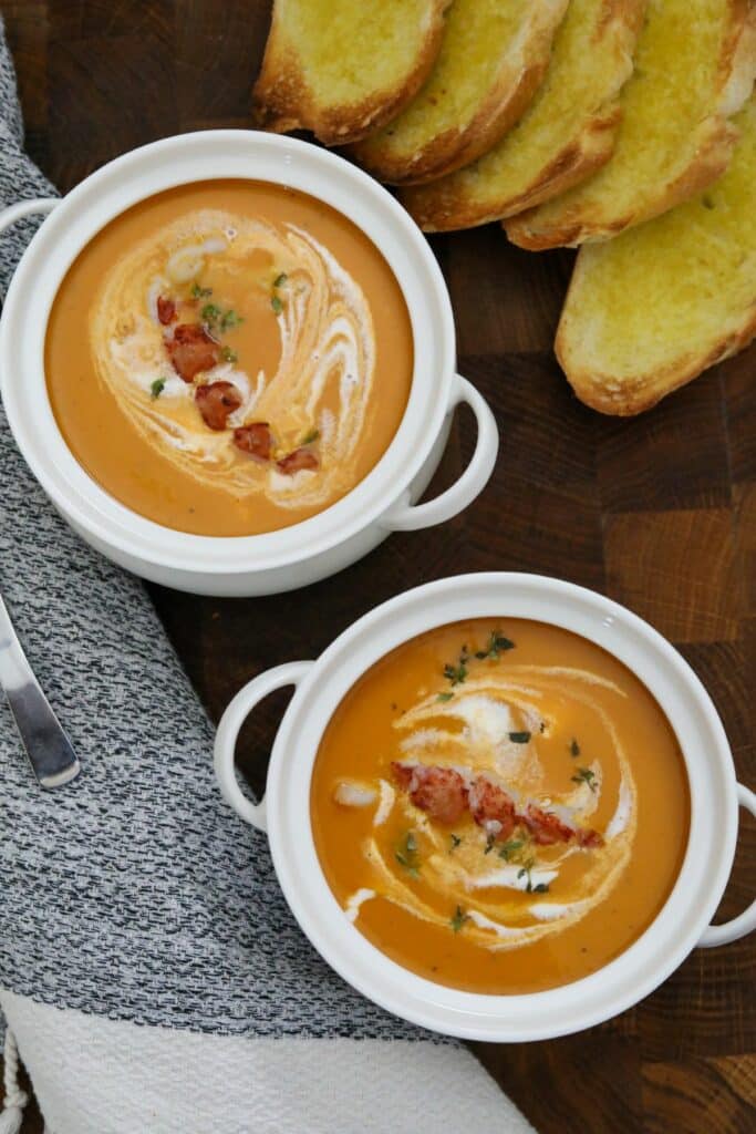 Two bowls of lobster bisque with toast.