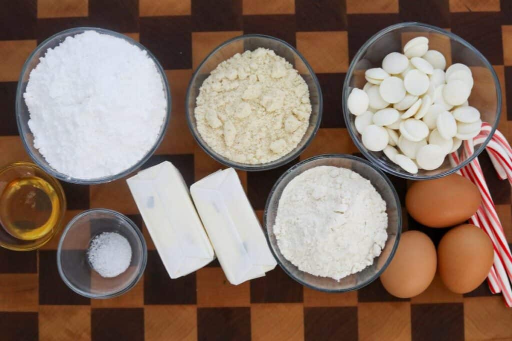 Ingredients for white chocolate peppermint madeleines on a wooden cutting board
