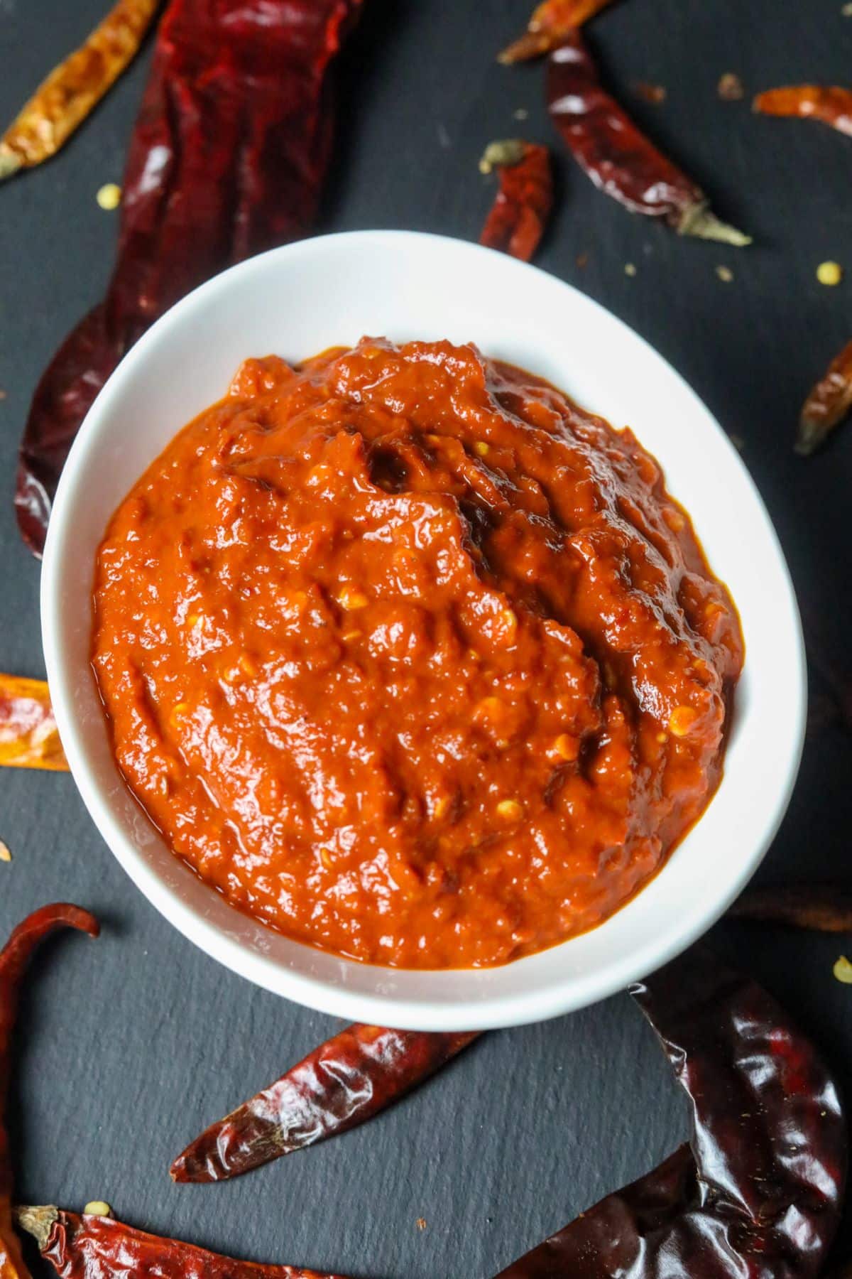 A white bowl of harissa on a black background
