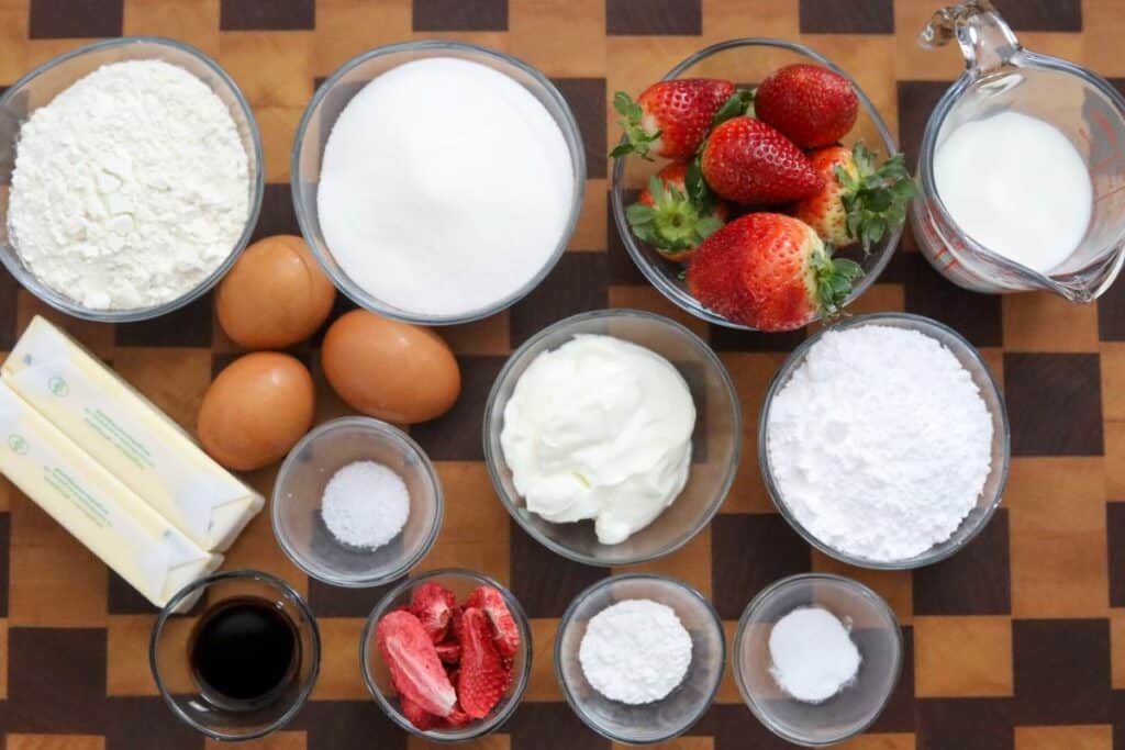 Ingredients for strawberry cupcakes on a wooden cutting board