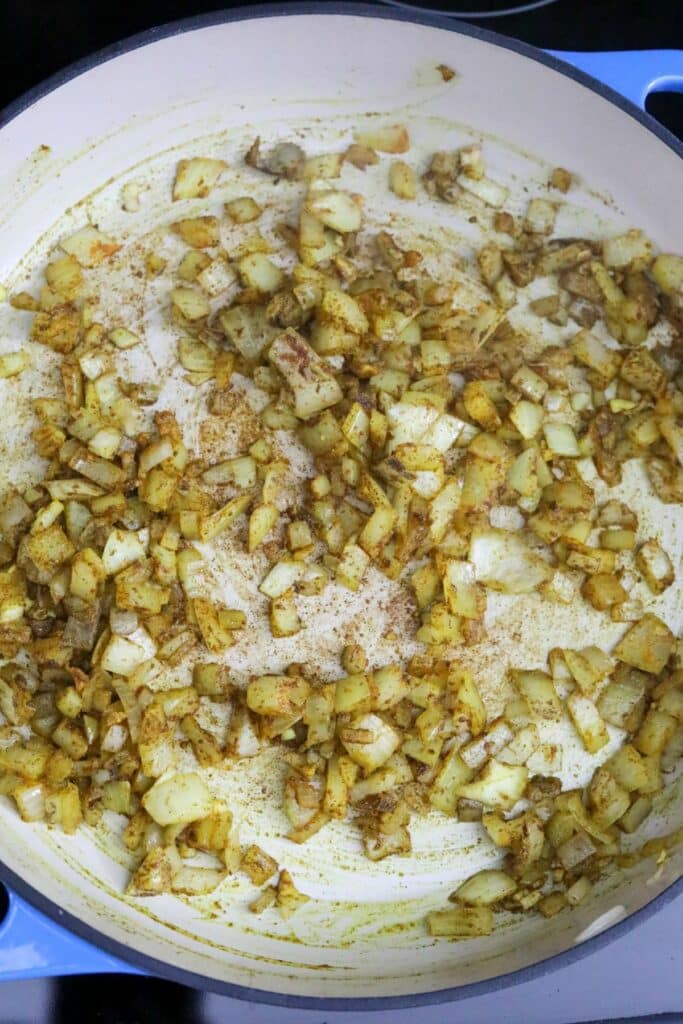 Onions in bloomed spices in a cast iron casserole dish