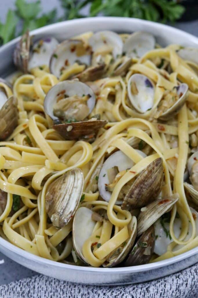 Close up of linguine with clams in a gray and white bowl